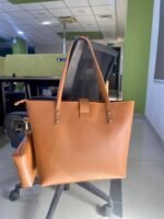 The spacious Caramel Tote Bag, available in a rich brown color, features a secure design with a locking system, a small pouch, and a comfortable leather strap. It offers ample storage space and is available in Pakistan.
